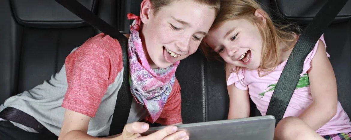 children looking at tablet in car