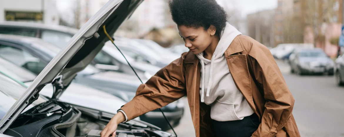 A woman looks under the bonnet of her car