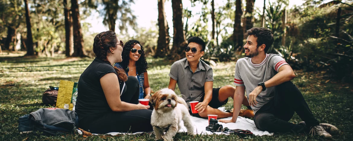 Friends and small dog enjoying picnic in woods