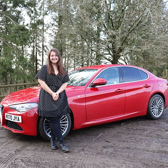 Woman smiling stood in front of Alfa Romeo Giulia
