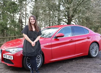 Woman smiling stood in front of Alfa Romeo Giulia